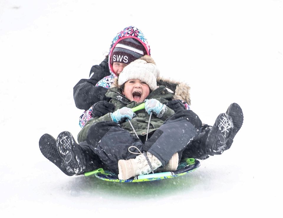Two 10-year-olds sled down a hill at Cedar