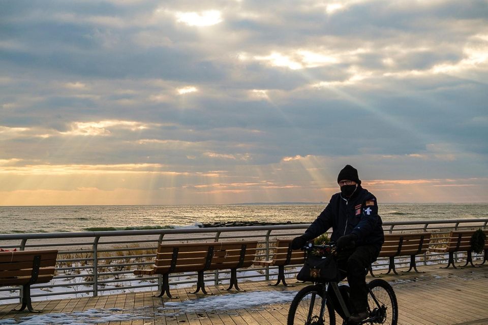 A bicyclist pedals along the boardwalk as faint