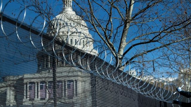 Razor wire is added Thursday atop a fence