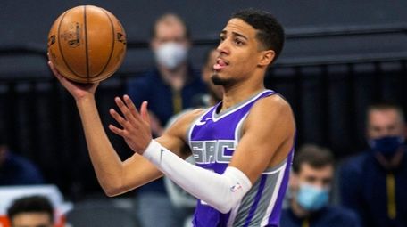 Kings guard Tyrese Haliburton, center, drives to the