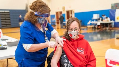 School nurse Cathy Williams vaccinates Jodi Messin, a
