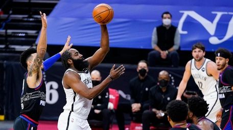 Nets' James Harden, center, goes up for a