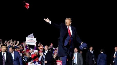 Then-President Donald Trump tosses MAGA hats at a