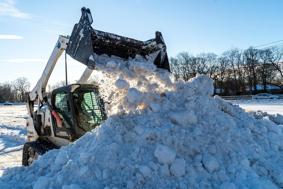 A man operating a payloader removes snow from