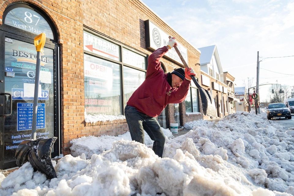 Carlos Ramos shovels the sidewalk along West Main