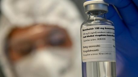 A bottle containing the drug remdesivir is held