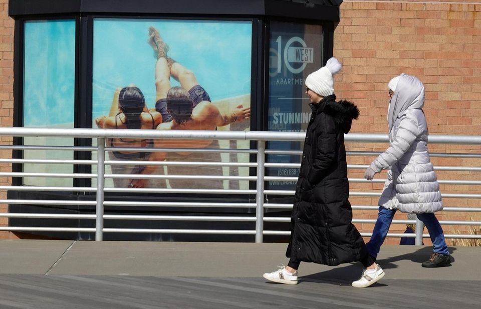 People bundled up in winter coats walk past