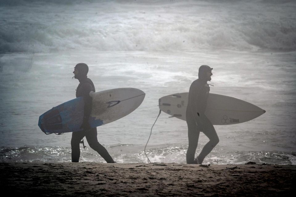 Surfer navigate the thick fog at Lido Beach