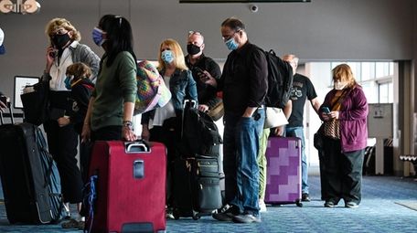Passengers wait in line at a Frontier Airlines