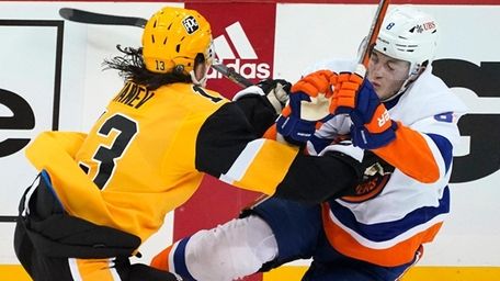 The Penguins' Brandon Tanev, left, checks the Islanders'
