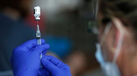 A nurse draws a syringe full of the