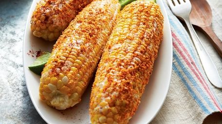 Corn on the cob is brushed with mayonnaise