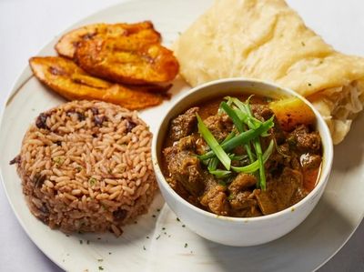 Curry goat with roti, fried plantains, rice and