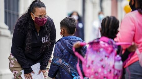 A staff member greets students as they arrive