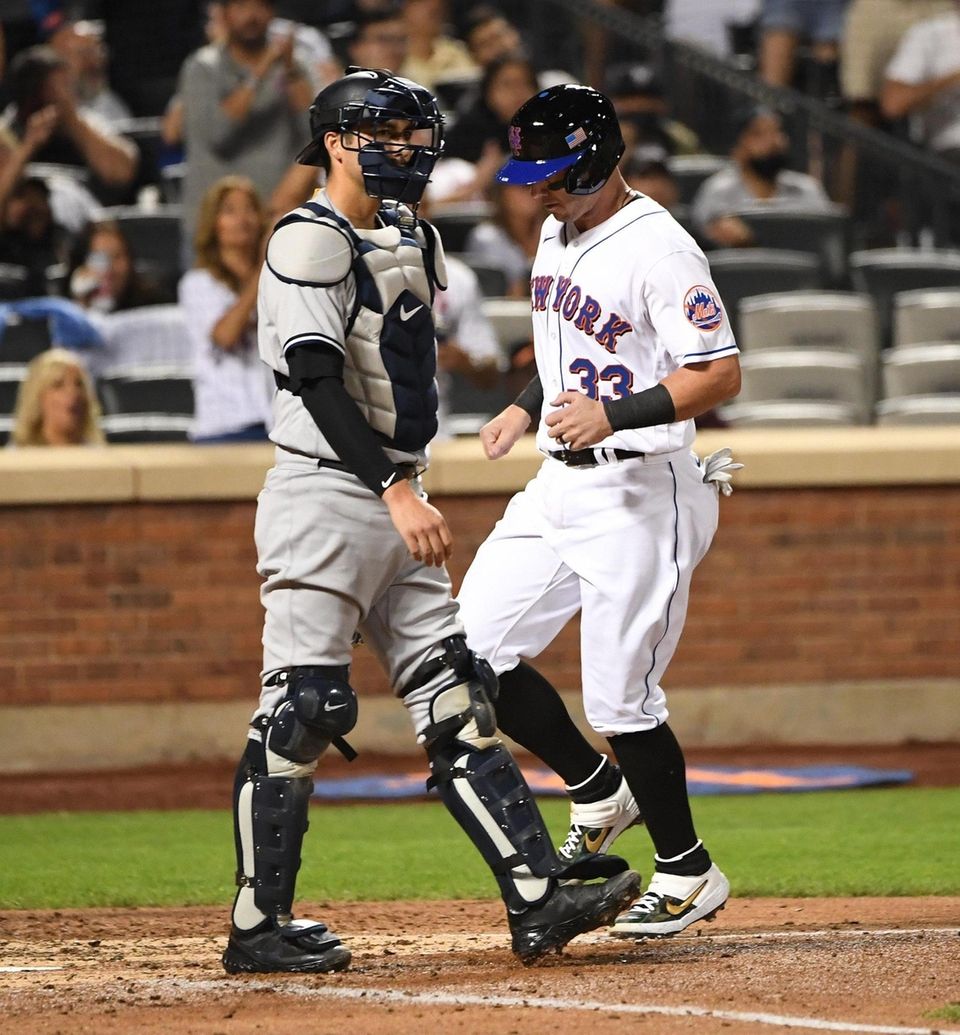 New York Mets catcher James McCann scores behind