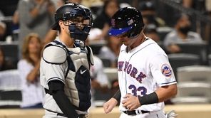 New York Mets catcher James McCann scores behind