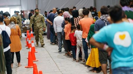 Afghan refugees line up for food in a