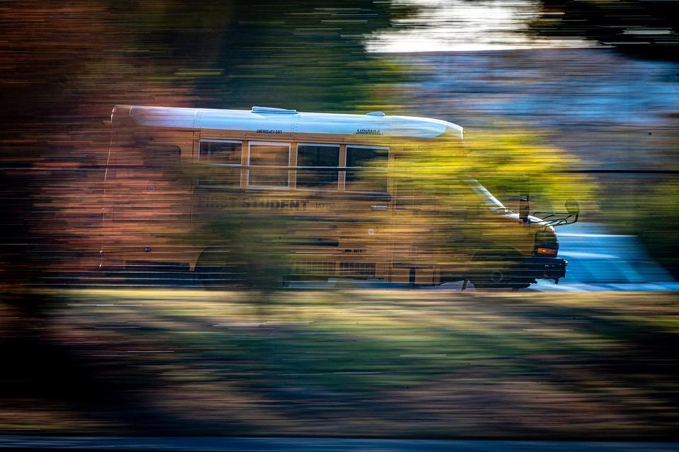 A school bus streaking past the autumn leave