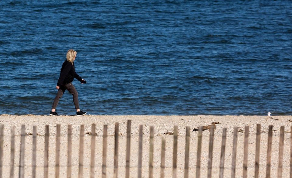 A woman walks along the beach at Sunken