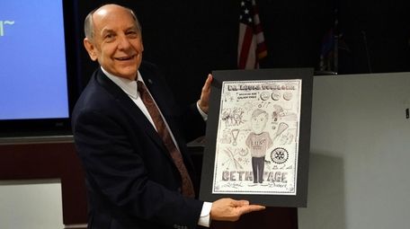 Louis Uccellini holds a drawing, created by students