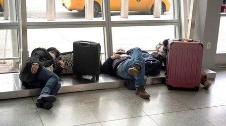 Travelers wait for flights at Kennedy Airport on