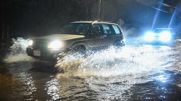 Cars naviage through flooded Granny Road in Medford