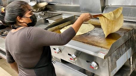 Annet Saunarine flips roti on the griddle at