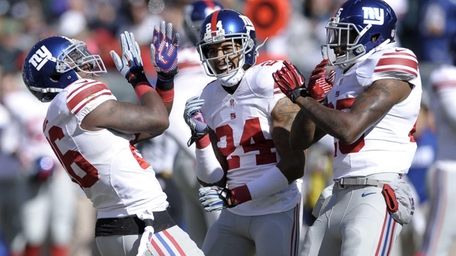Antrel Rolle (26) celebrates with teammates Will Hill