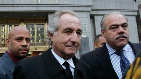 Bernard Madoff, center, walks out from federal court