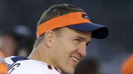 Peyton Manning smiles while standing on the sideline