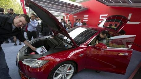 Customers and journalists examine a Tesla Model S