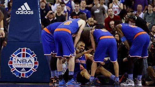 Knicks center Tyson Chandler, bottom, is helped back