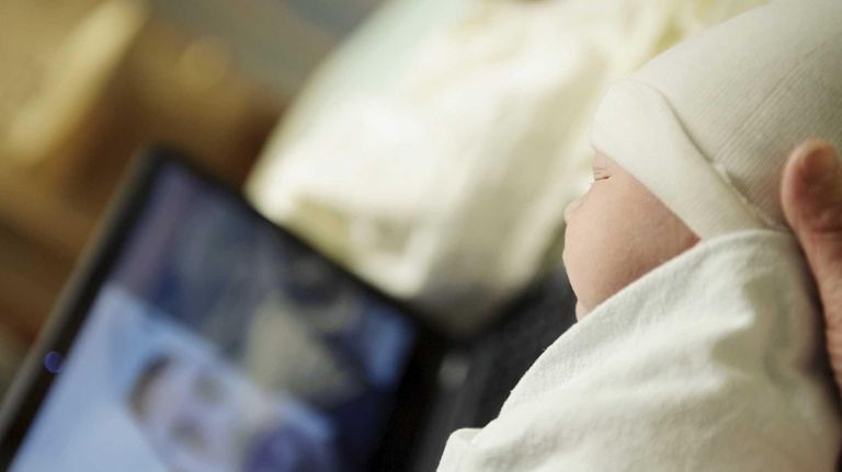 A newborn baby being shown to somebody over