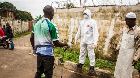 A health worker sprays disinfectant on a person