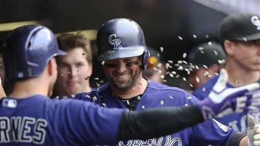 The Colorado Rockies' Brandon Barnes, front, tosses a