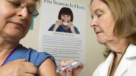 Nurse Practitioner Catherine Shannon, right, gives the flu