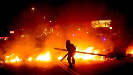 A protester adds wood to a fire burning